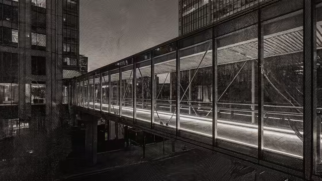 Una pasarela de vidrio iluminada que une dos edificios contemporáneos